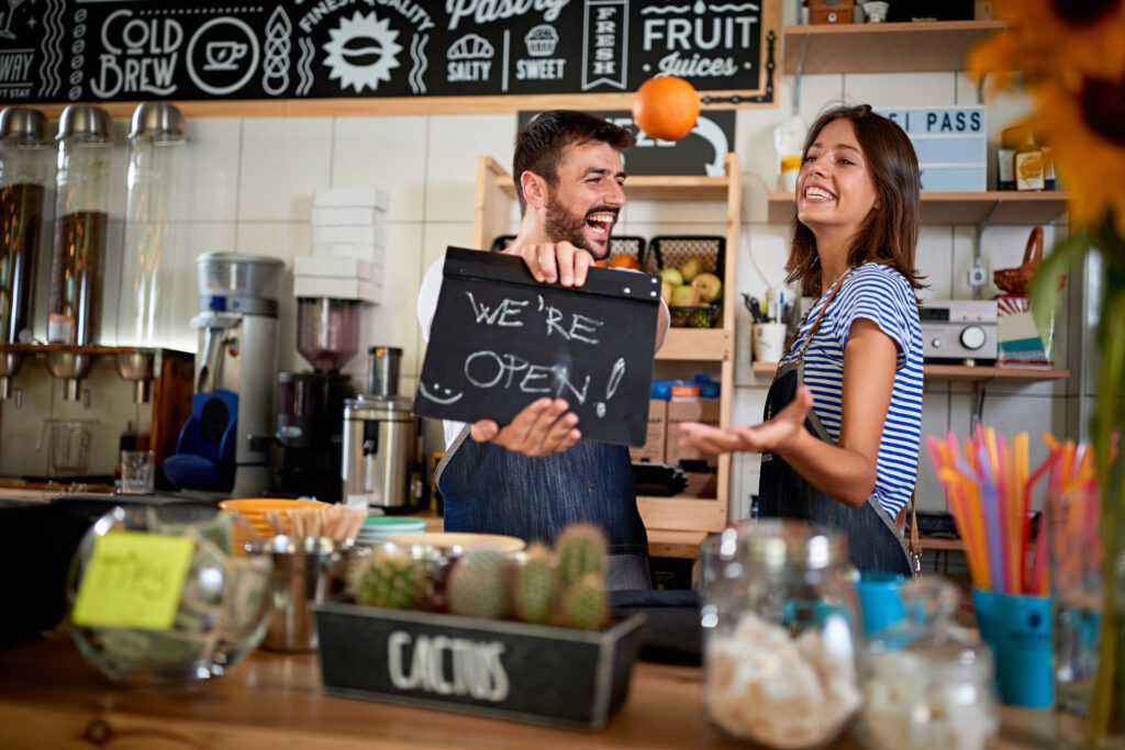 Business owner holding Open Sign. Proud man and woman opening their store